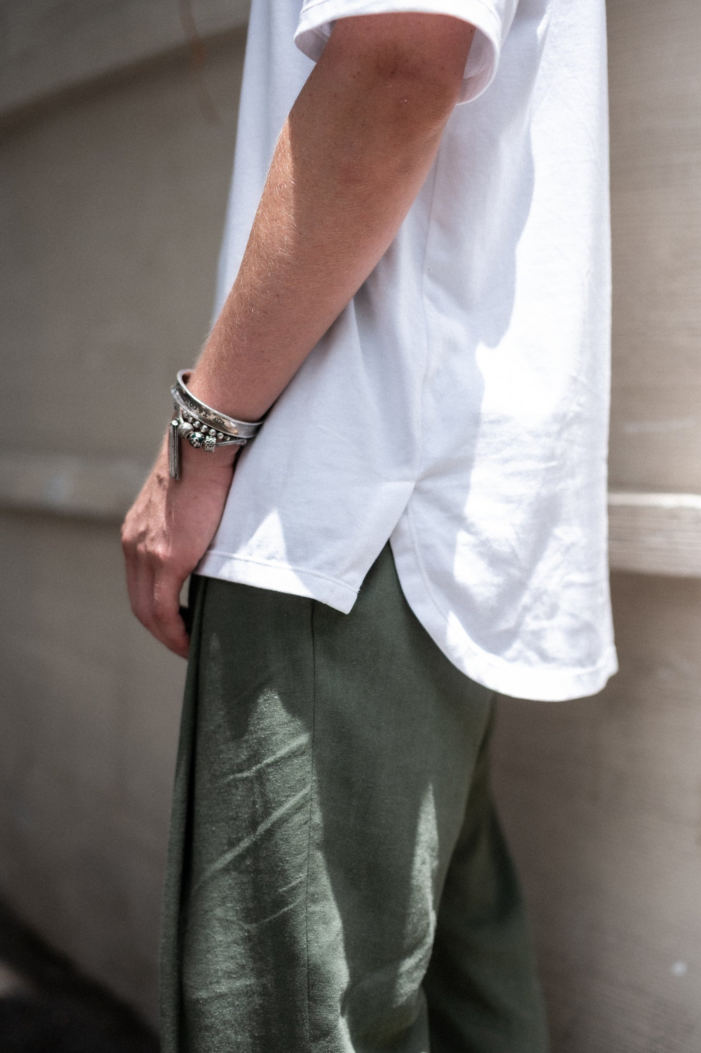 Person wearing a white shirt and green pants on a sidewalk