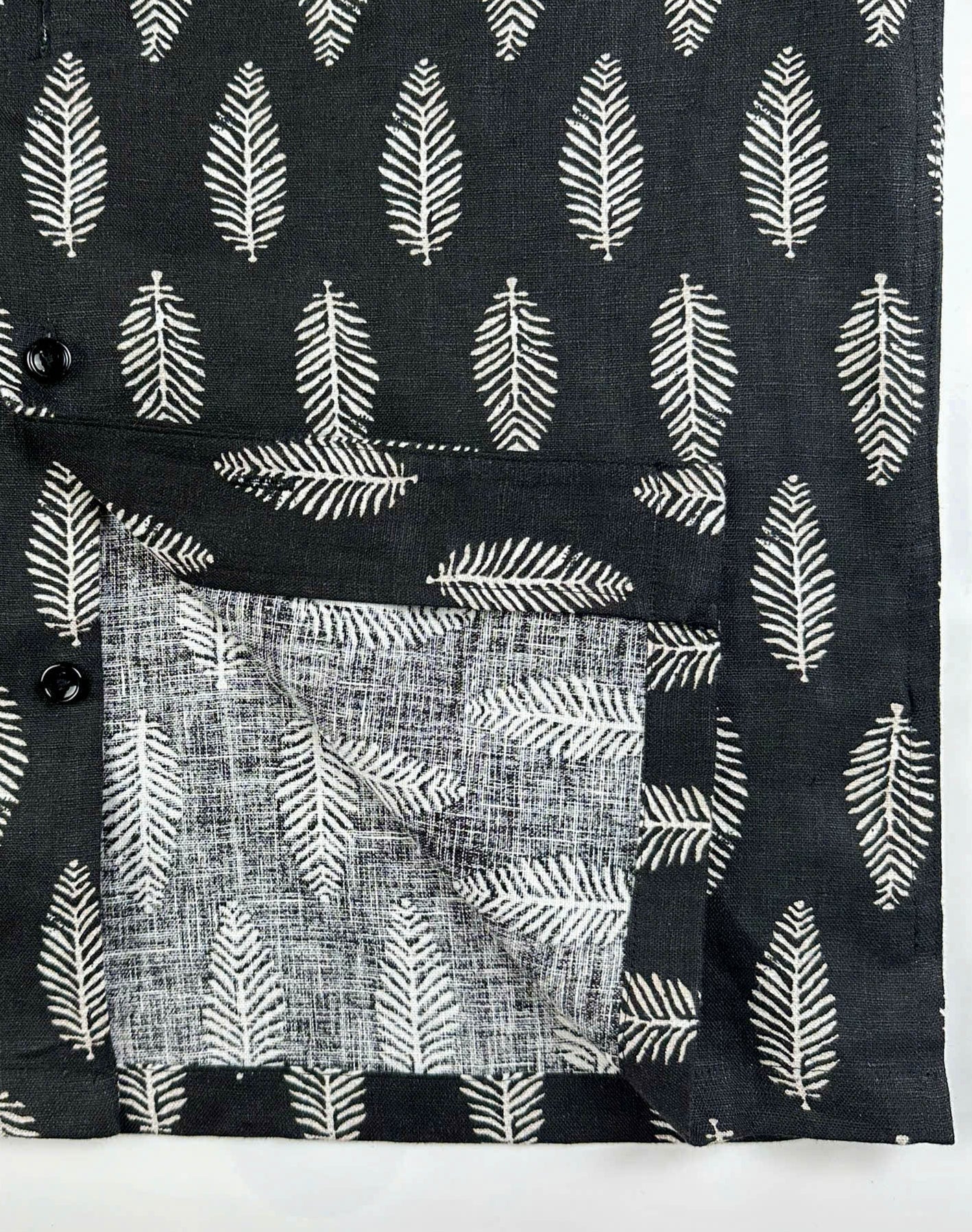 Seam and quality detail of black linen shirt with silver fern pattern