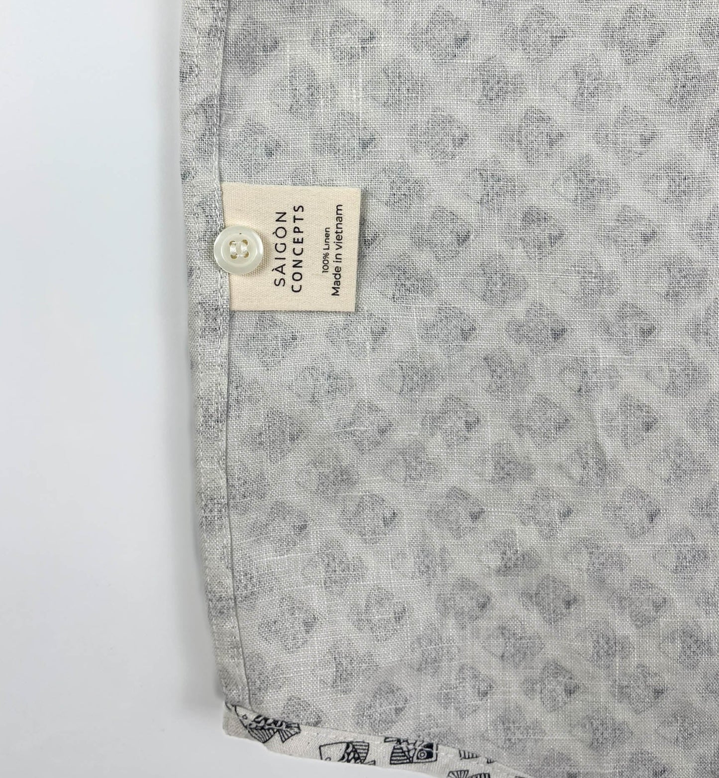 Tiny Black Fish linen long sleeve button-up shirt lay flat care label detail view, small fish print on natural white base