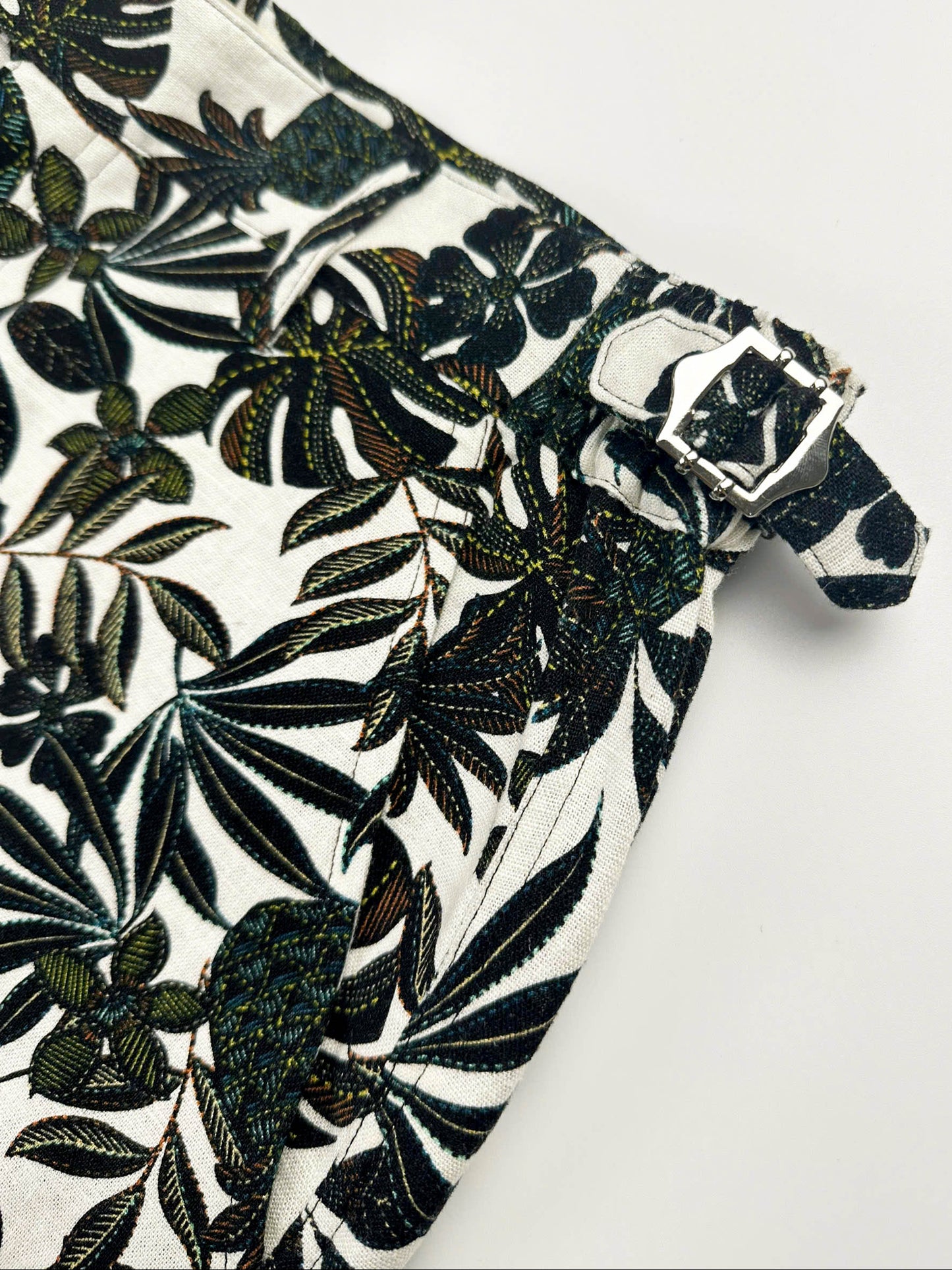Metal slide buckle detail on Black tropical floral patterned linen shorts on a natural white background