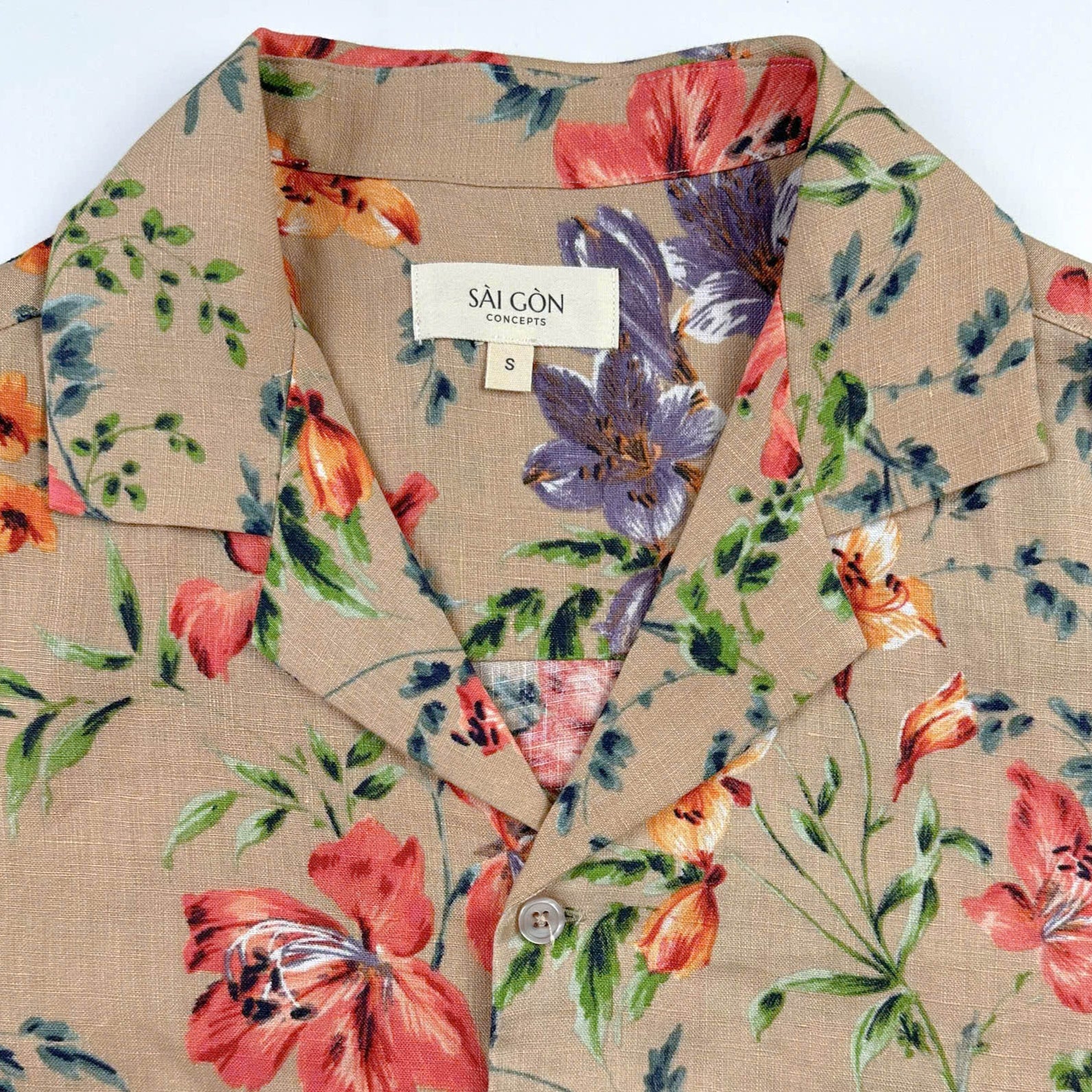 Vibrant Floral patterned linen Hawaiian style shirt on a sandy beige background