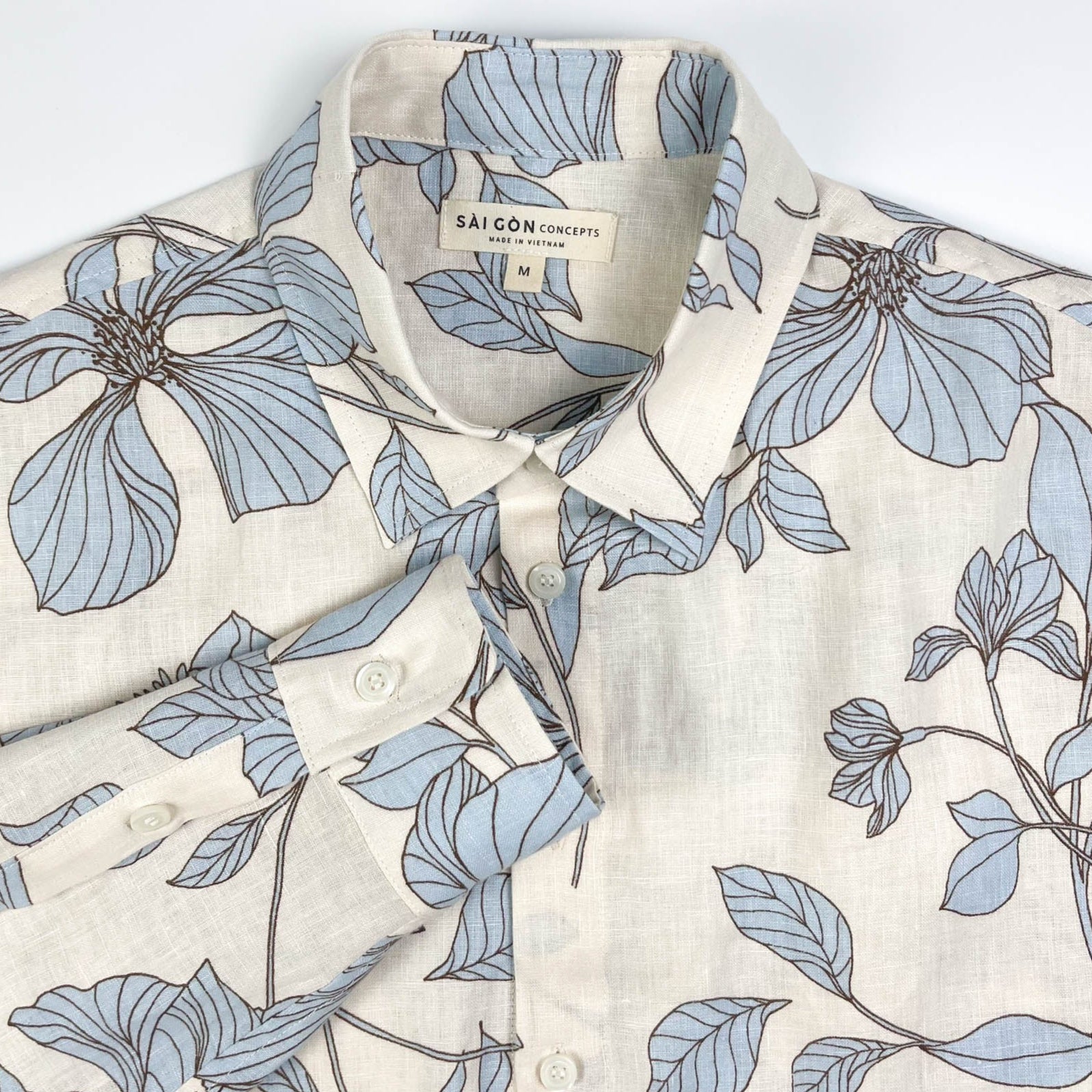 Blue Hibiscus linen long sleeve button-up shirt lay flat neck view, light blue hibiscus print on natural white linen