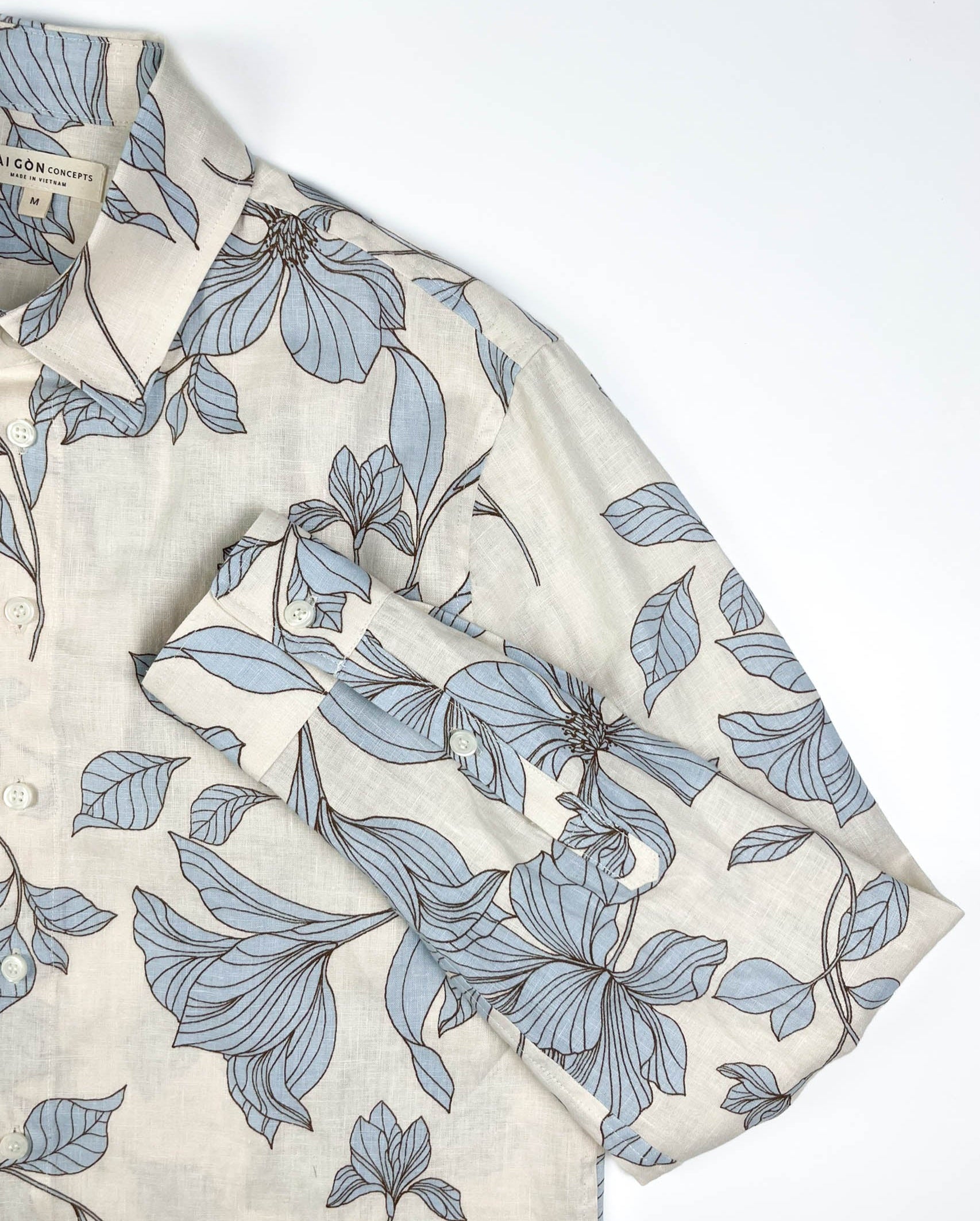 Blue Hibiscus linen long sleeve button-up shirt lay flat sleeve detail view, light blue hibiscus print on natural white linen