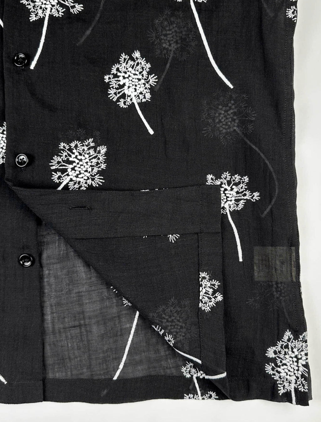 close up quality stitching detail of Black linen shirt with white embroidered dandelions 