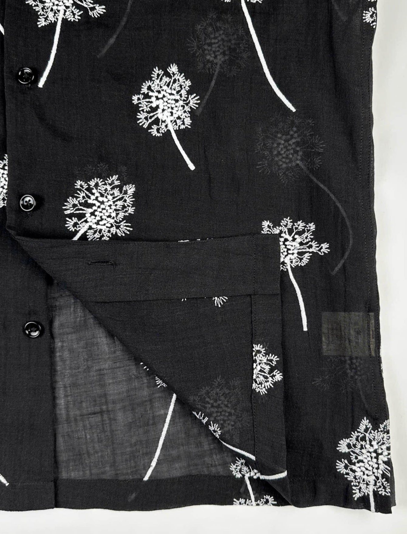 close up quality stitching detail of Black linen shirt with white embroidered dandelions 