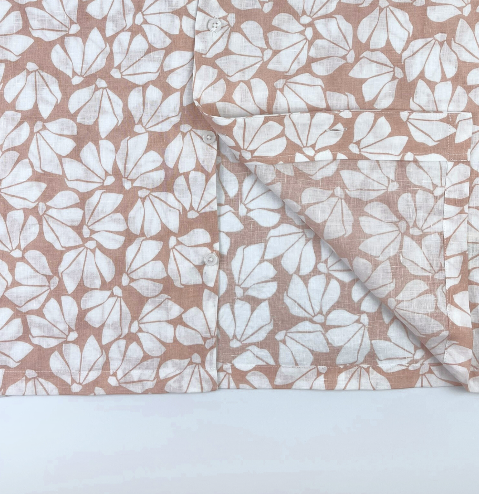 Close-up of white floral print on pink linen fabric, breathable natural fibre Hawaii shirt - seam detail