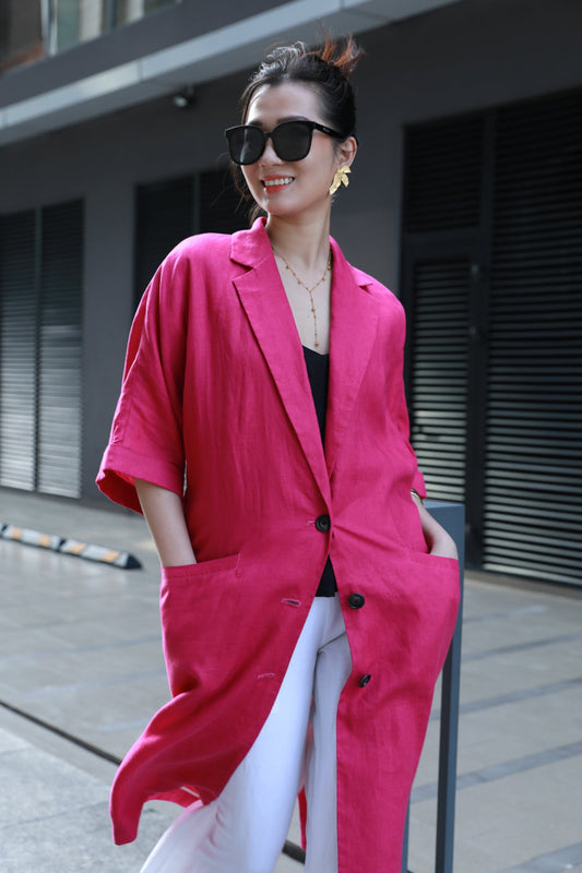Woman wearing a fuchsia pink coat and sunglasses outdoors.