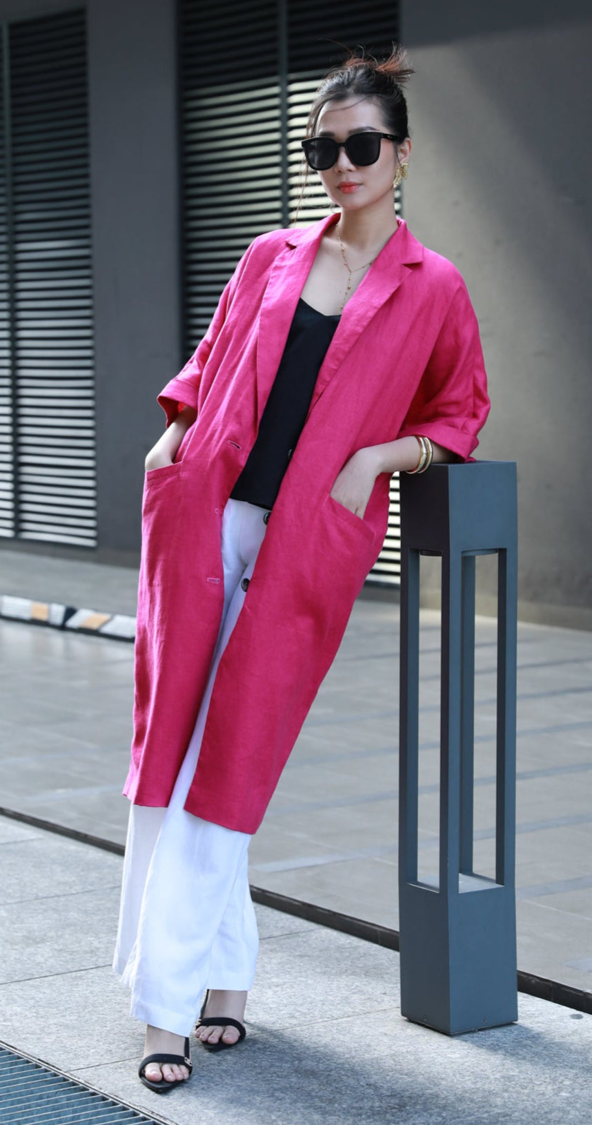 Woman in a fuchsia pink coat standing on a sidewalk