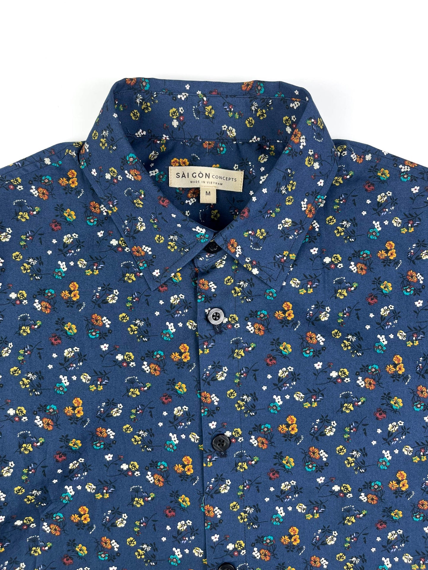 Indigo Meadow cotton short sleeve button-up shirt lay flat neck view, meadow floral print on indigo base fabric