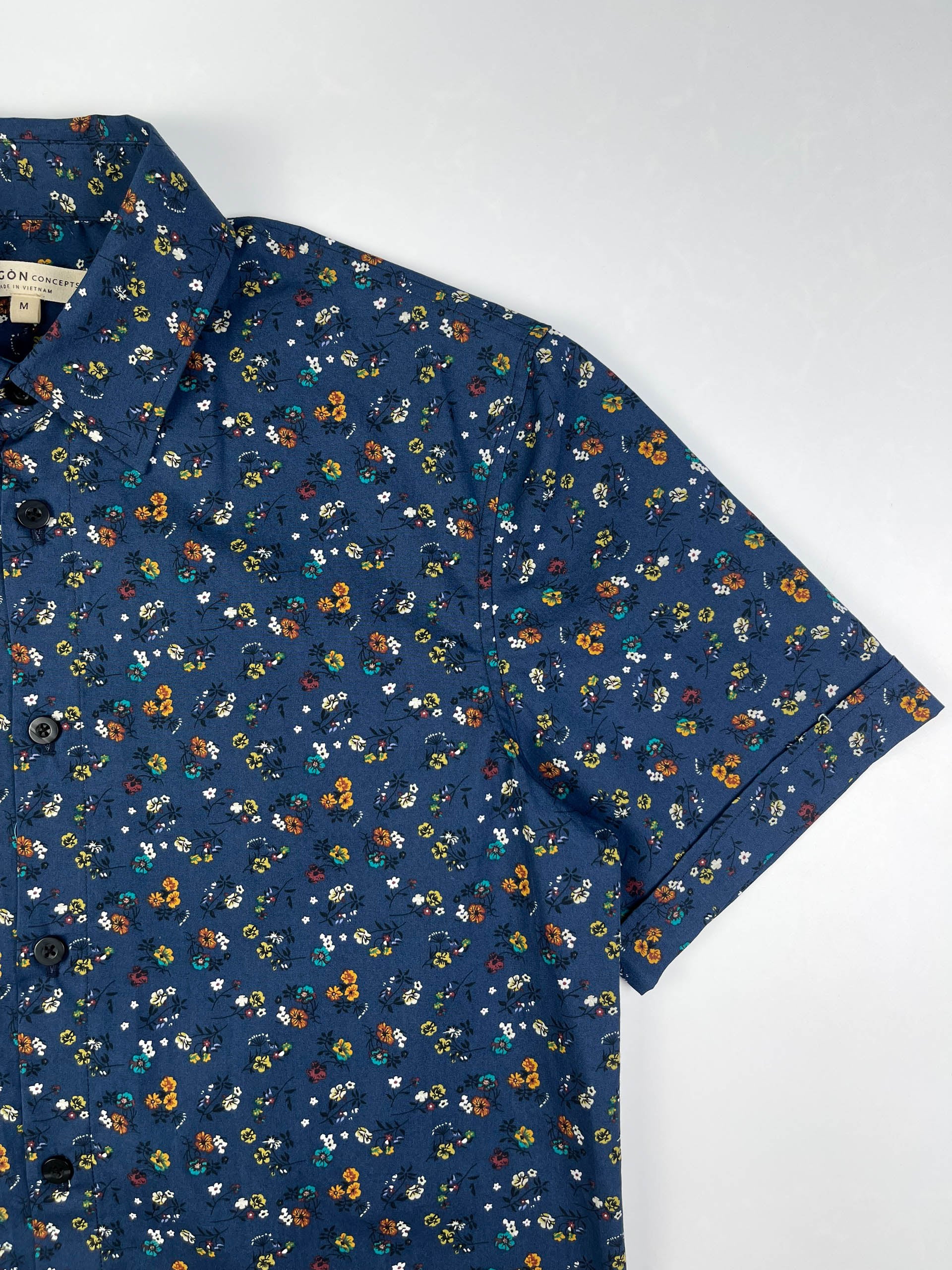 Indigo Meadow cotton short sleeve button-up shirt lay flat sleeve detail view, meadow floral print on indigo base fabric