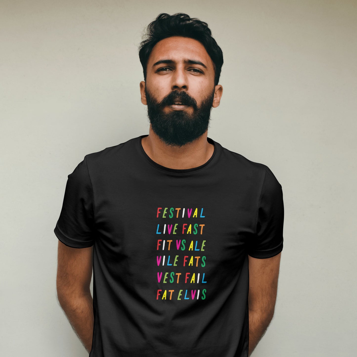 Man wearing a black t-shirt with rainbow coloured text against a plain background