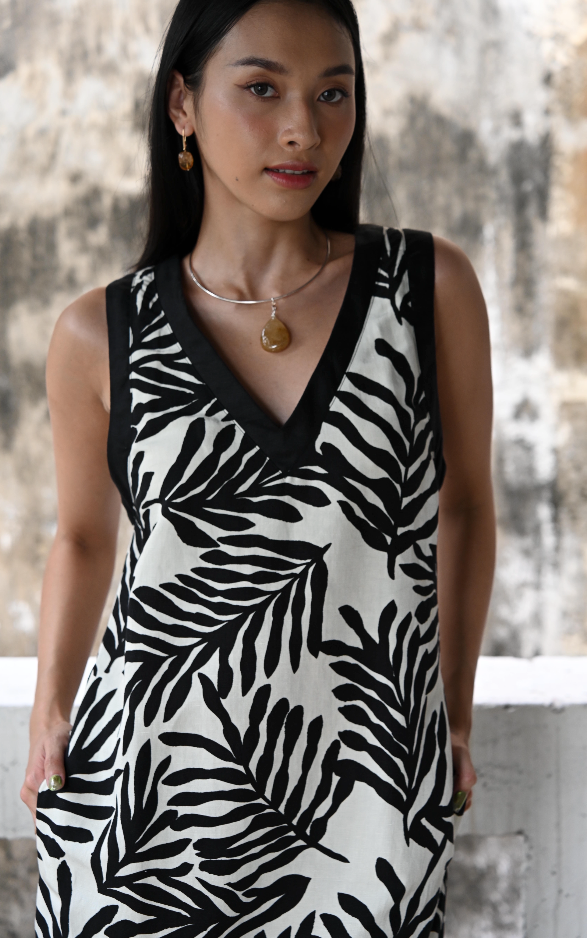 Woman wearing a black and white patterned dress against a textured wall.
