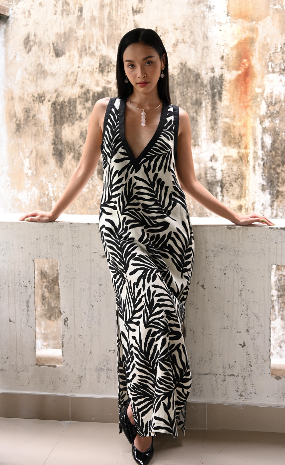 Woman wearing a black and white patterned dress standing on a balcony.