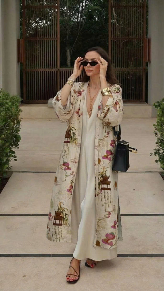 Woman arriving at tropic resort hotel wearing a Saigon Concepts kimono-style robe with brown pagodas and pink Asia inspired swirls printed on a cream linen organza fabric.  