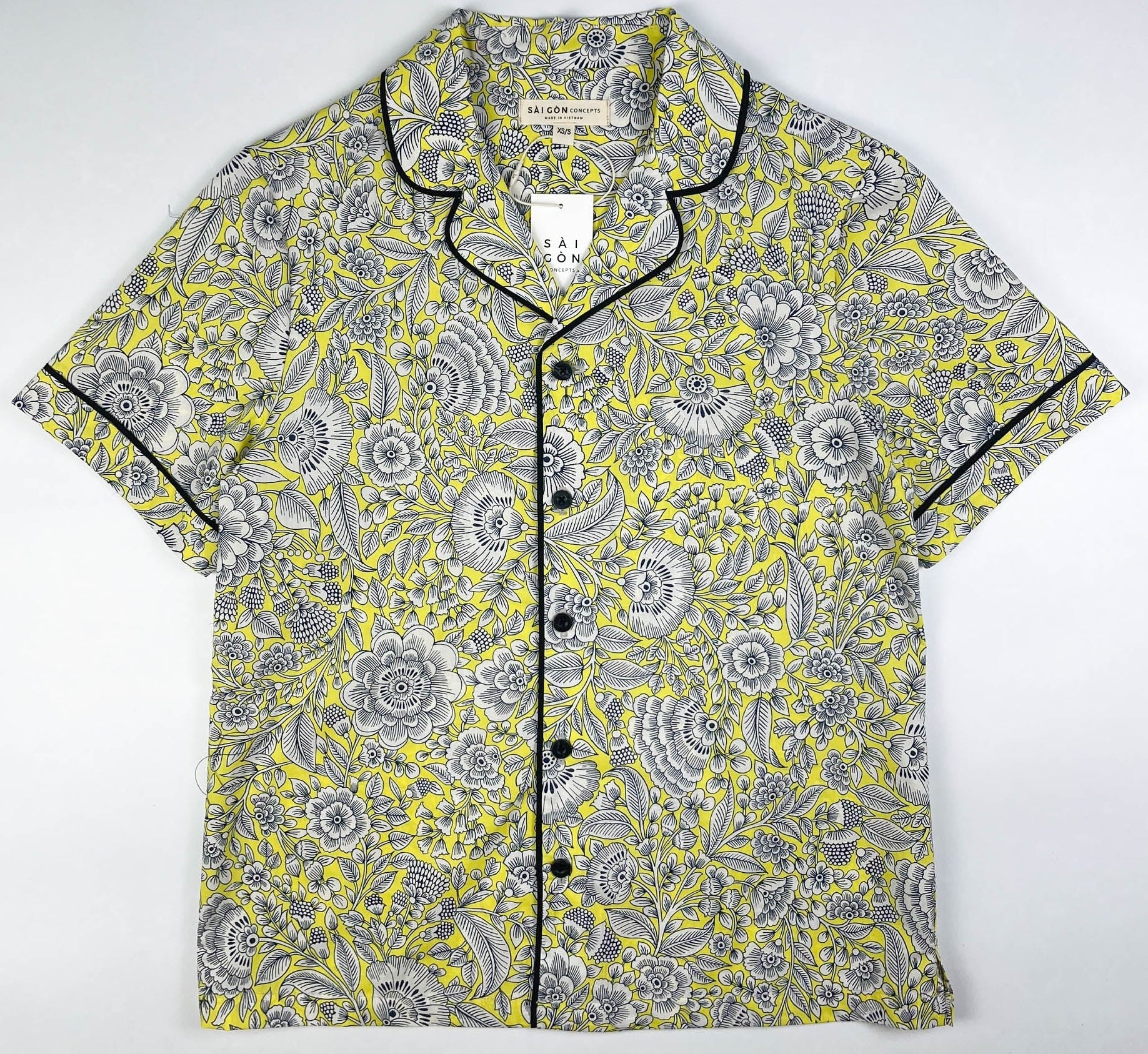 Sunshine Chintz short sleeve pyjama top lay flat, yellow cotton with grey floral print with black contrast piping on sleeves, collar and front. Saigon Concepts
