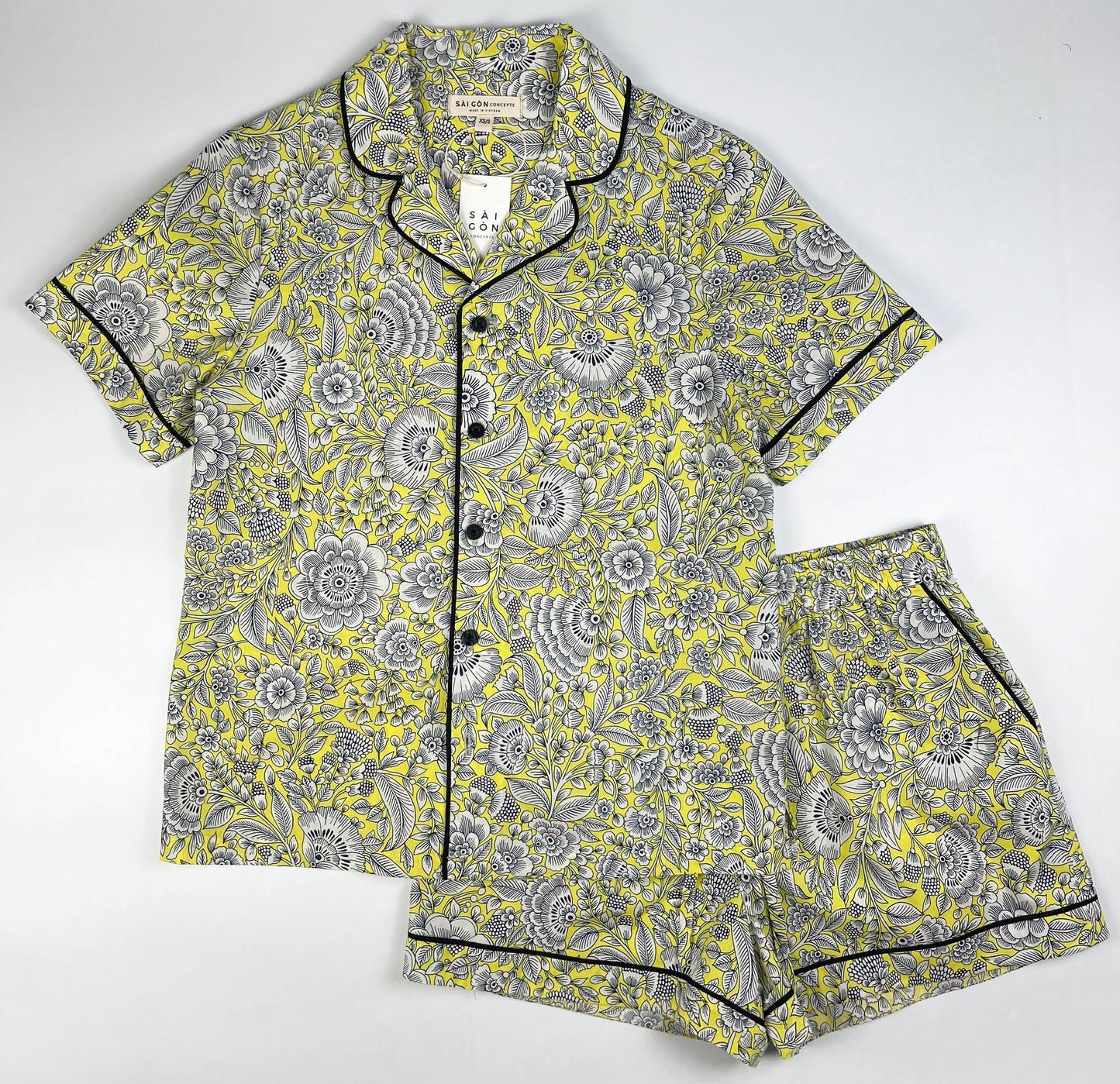 Sunshine Chintz short sleeve pyjama top with matching shorts lay flat, yellow cotton with grey floral print with black contrast piping. Saigon Concepts