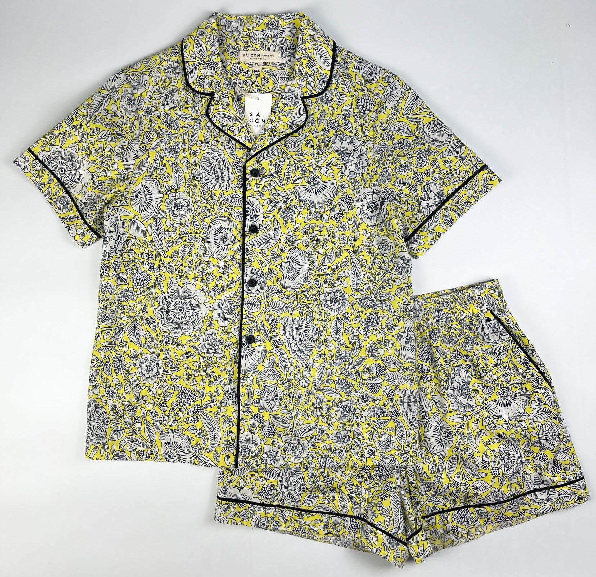 Sunshine Chintz short sleeve pyjama top with matching shorts lay flat, yellow cotton with grey floral print with black contrast piping. Saigon Concepts