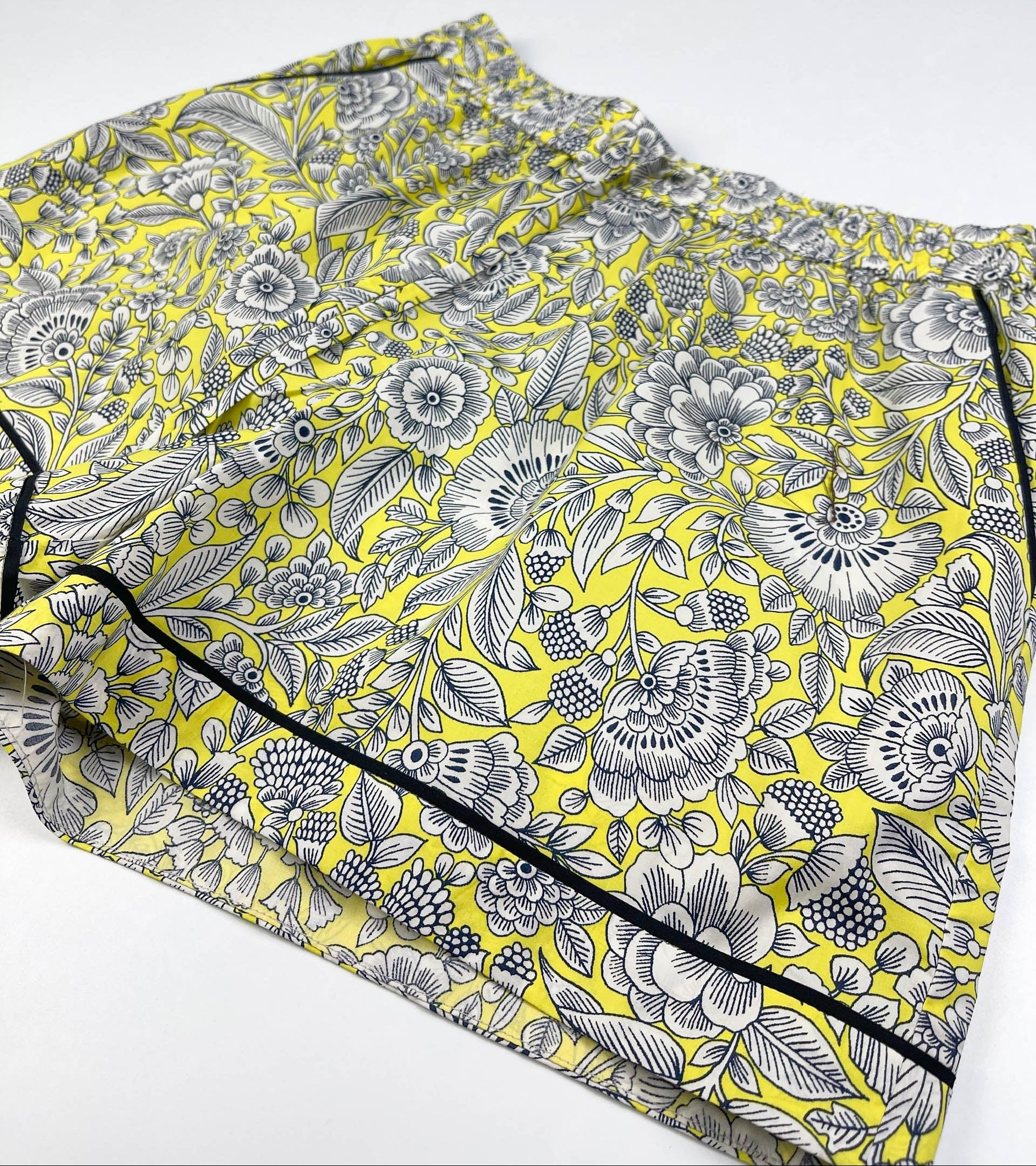 Sunshine Chintz pyjama shorts lay flat side view image featuring black contrast piping on leg seams and side pocket. Yellow cotton with grey floral print - Saigon Concepts