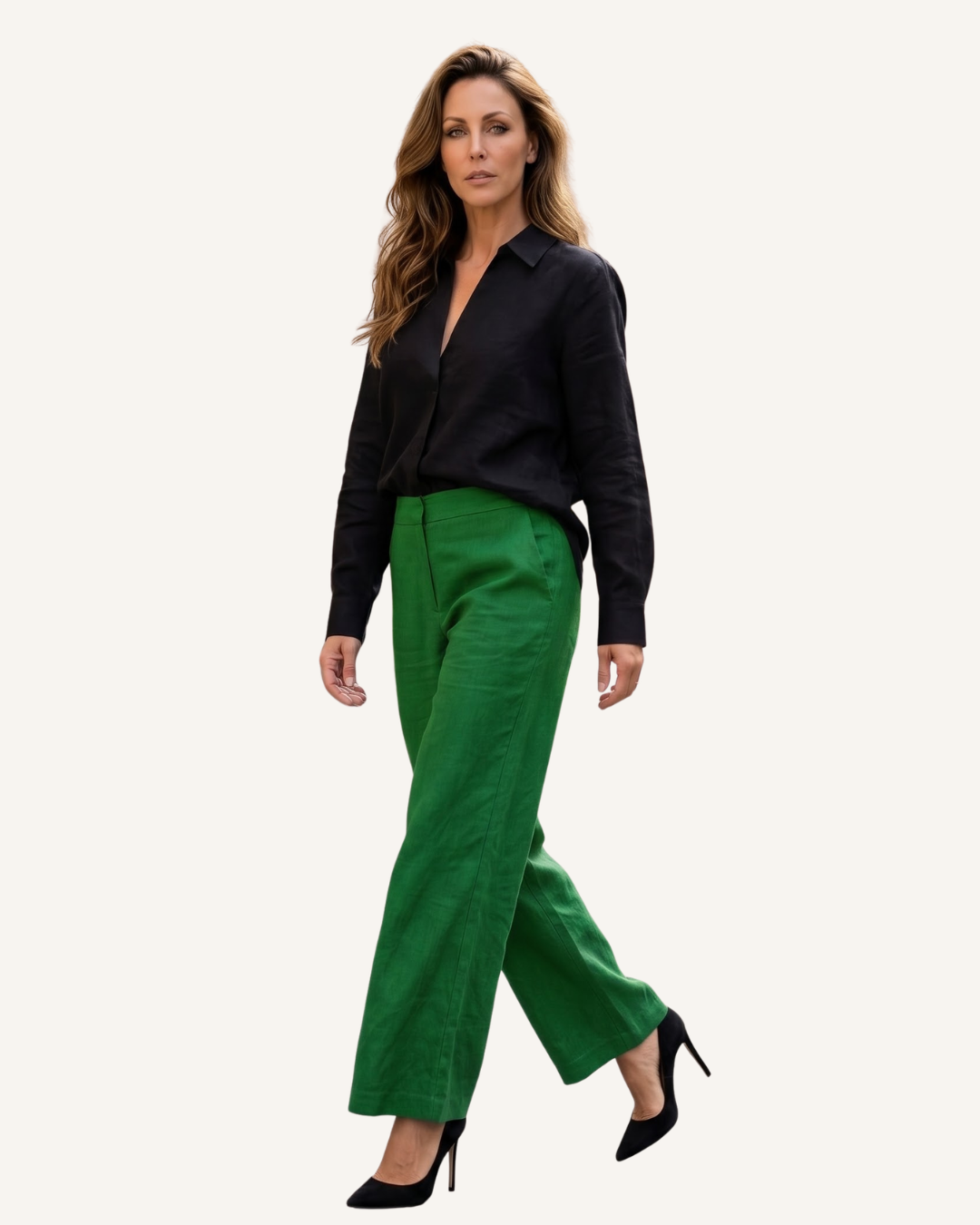 Female model wearing a black long-sleeve blouse with emerald green wide-leg pants and black heels on a neutral studio background.