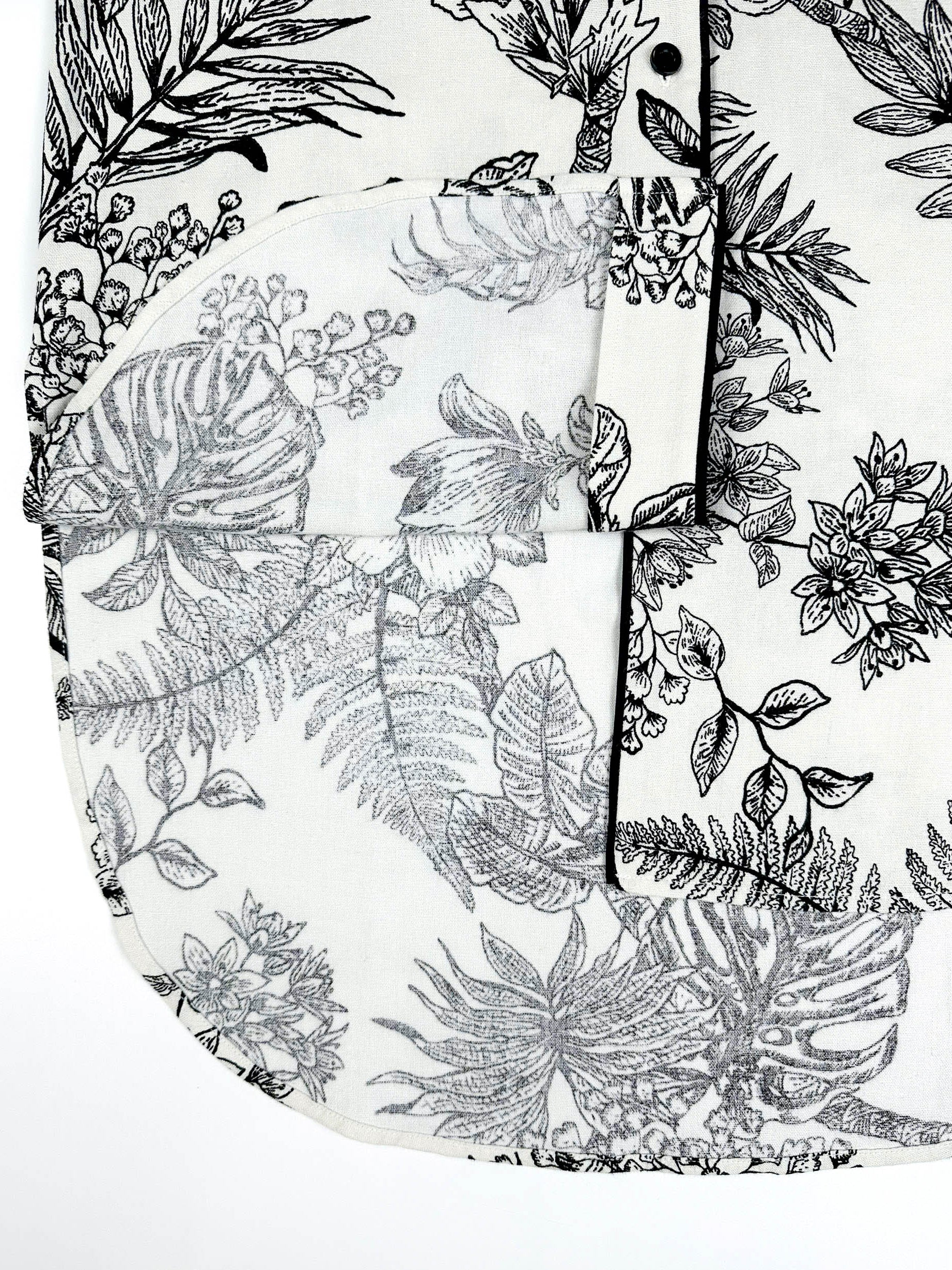Saigon Concepts Botanical Noir Longline PJ Top with black floral etched drawing on white linen - hem detail view with contrasting black piping.