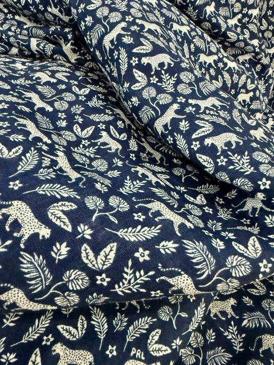 close up of navy blue linen fabric with white leopards and leaf pattern 