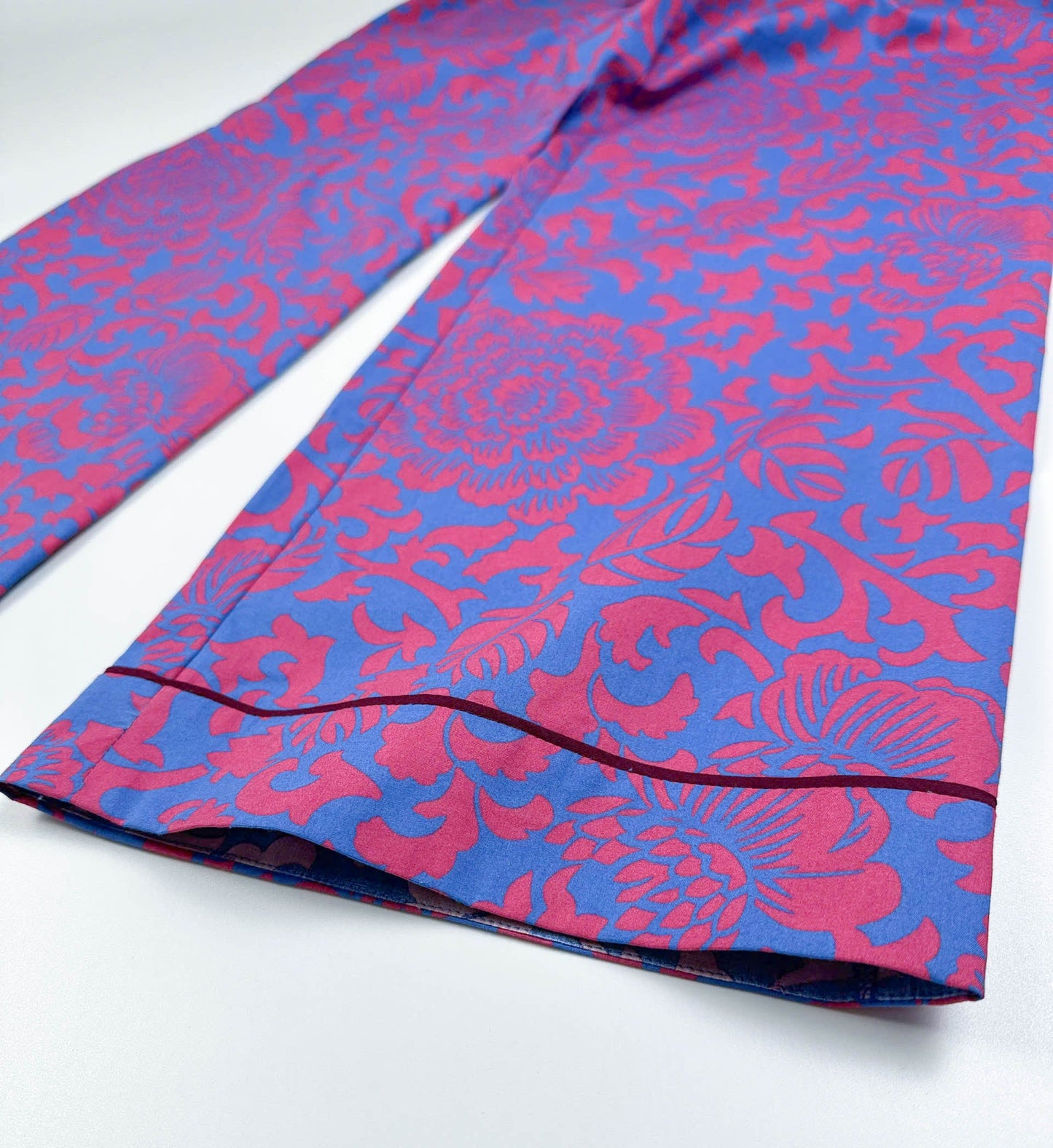 Saigon Concepts - close-up of Jardin Royale PJ leg detail in cotton fabric showing vibrant red-pink and sea note blue floral print with dark wine piping trim detail at the feet