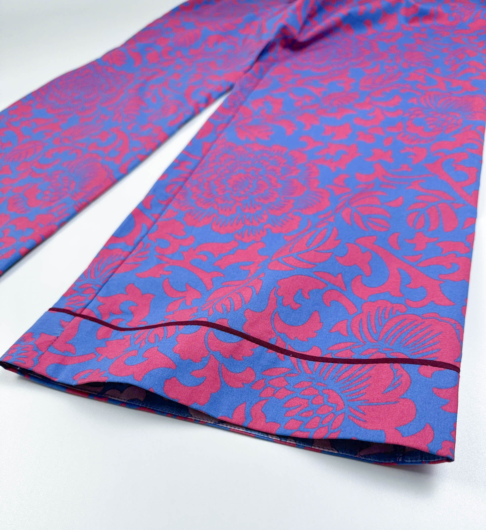 Saigon Concepts - close-up of Jardin Royale PJ leg detail in cotton fabric showing vibrant red-pink and sea note blue floral print with dark wine piping trim detail at the feet