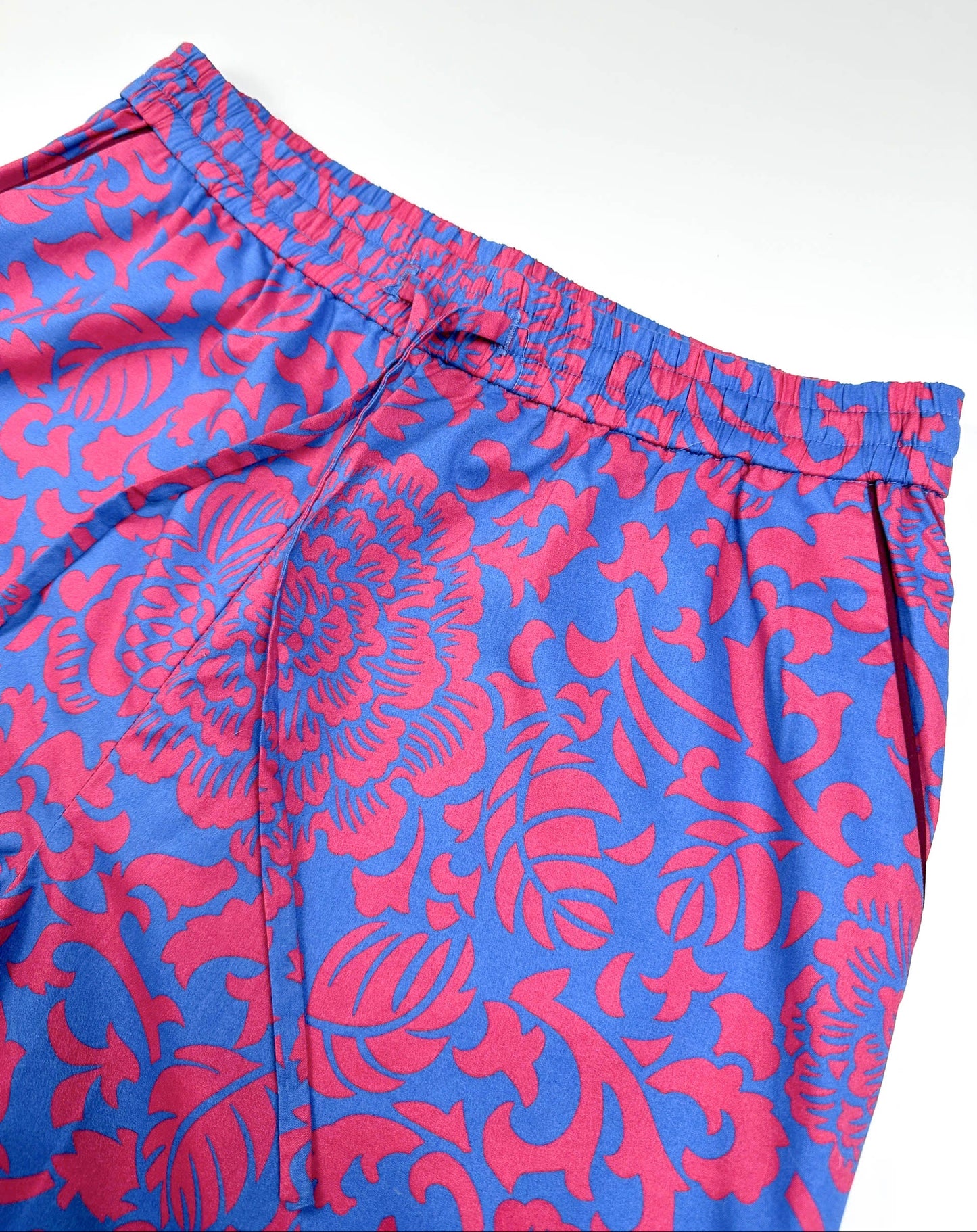 Saigon Concepts Close-up of Jardin Royale PJ waistband and drawcord in cotton fabric showing vibrant red-pink and sea note blue floral print with dark wine piping trim on pocket