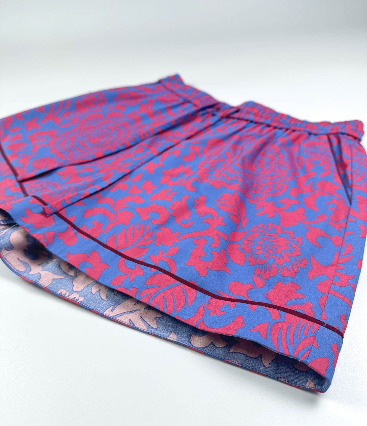 Saigon Concepts Jardin Royale lounge pyjama shorts in 100% cotton with red-pink floral print on a sea note blue background with contrasting wine trim - side view detail - Lounge to Street collection made in Vietnam