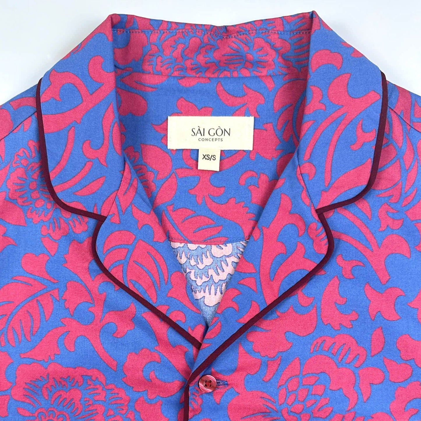 Saigon Concepts Jardin Royale lounge pyjama top in 100% cotton with red pink floral print on blue background with contrasting wine trim - close up neck view. Lounge to Street collection made in Vietnam