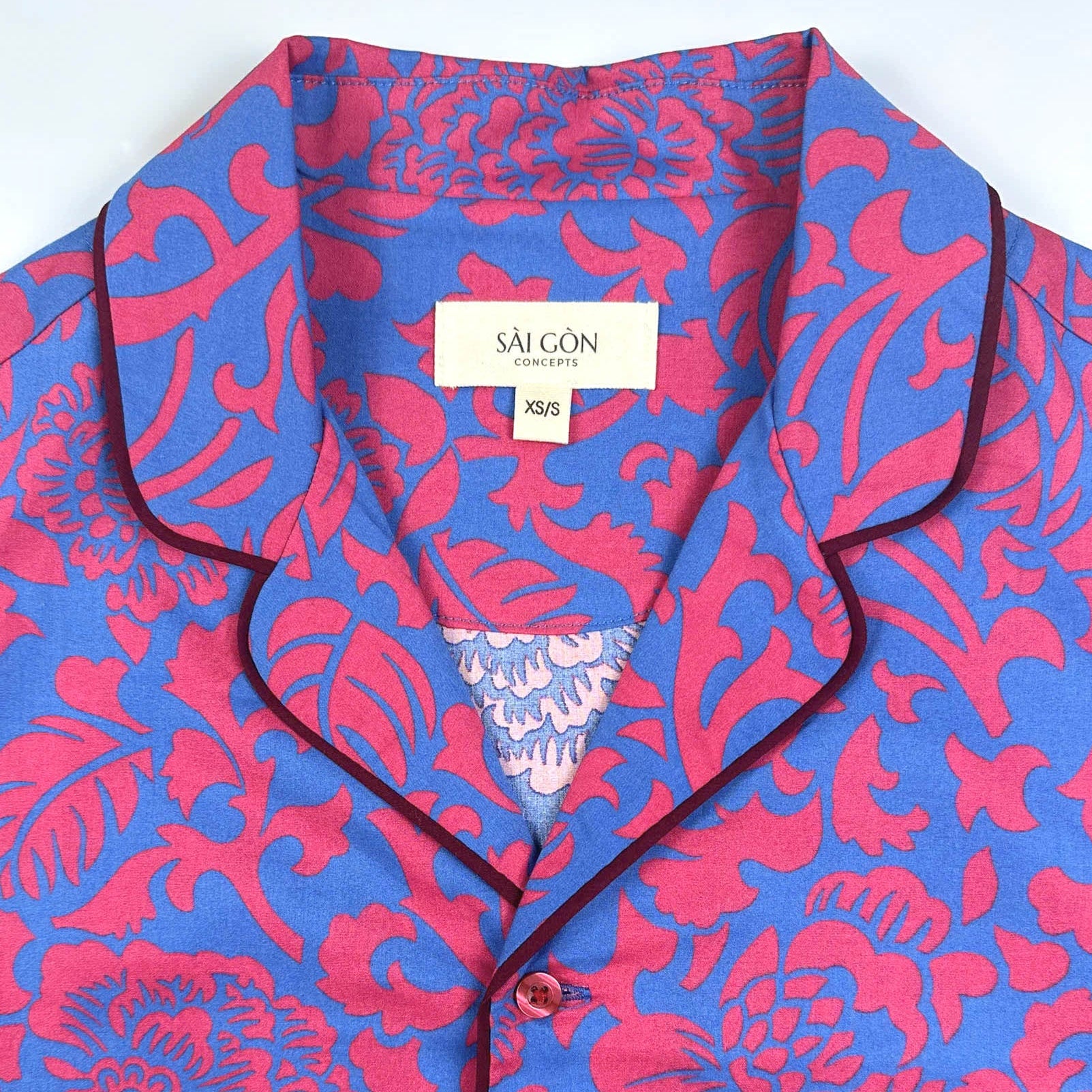 Saigon Concepts Jardin Royale lounge pyjama top in 100% cotton with red pink floral print on blue background with contrasting wine trim - close up neck view. Lounge to Street collection made in Vietnam