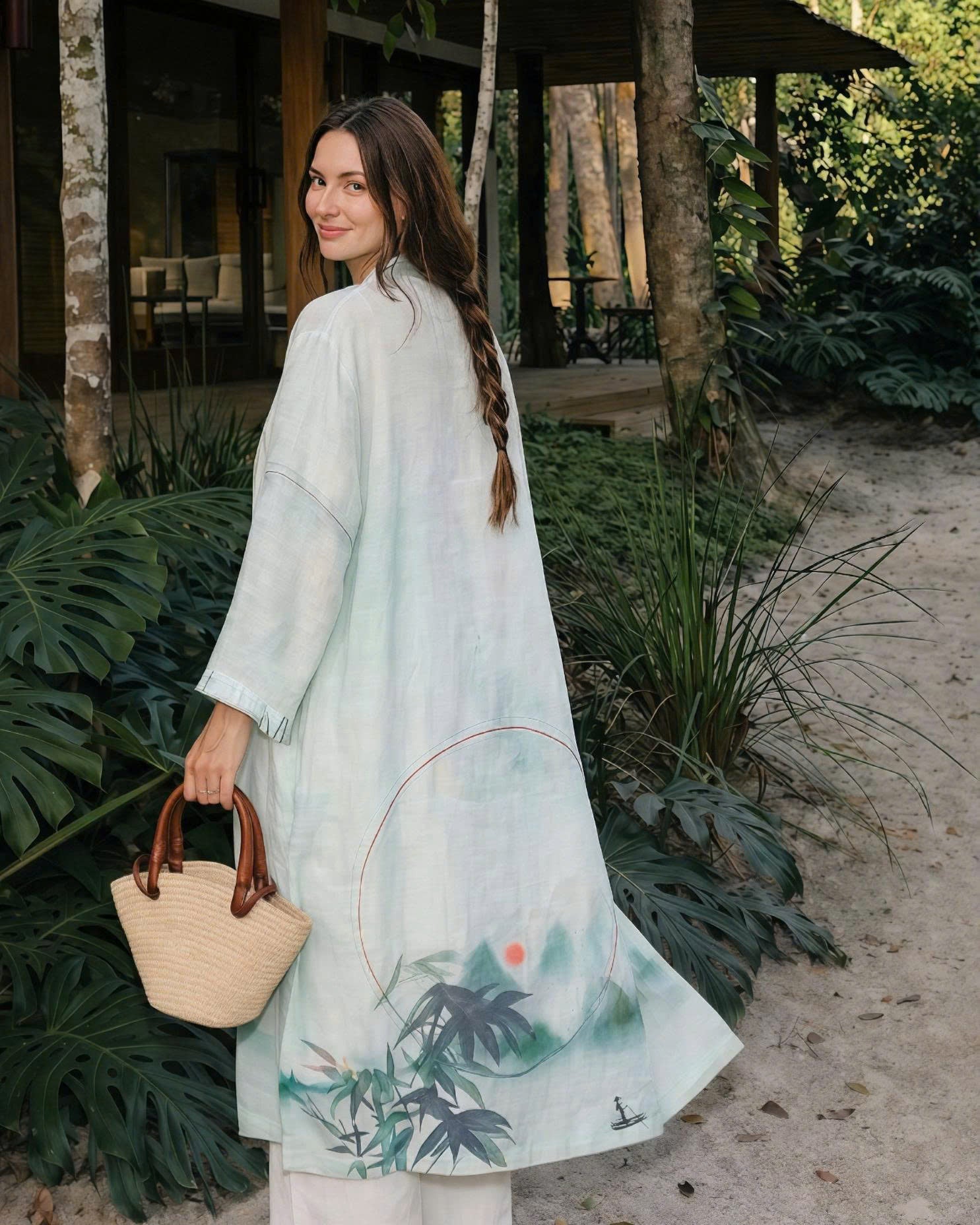 Woman in a light blue kimono-style roe with asian pattern standing in a natural resort setting.