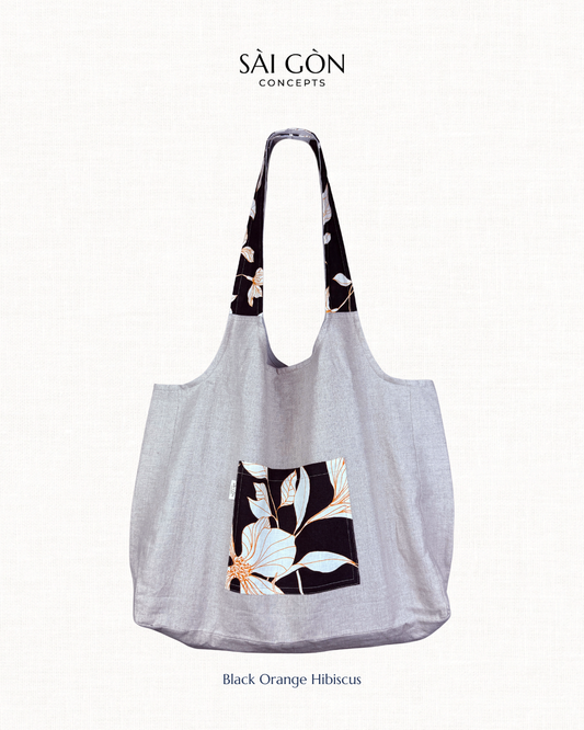 Saigon Concepts own beach tote bag with orange hibiscus floral design detail on pockets and strap, on a white background