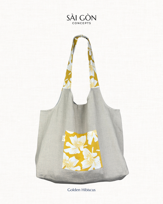 Saigon Concepts Natural Linen Beach Tote Bag with golden hibiscus print on pocket and handles on a natural linen bag