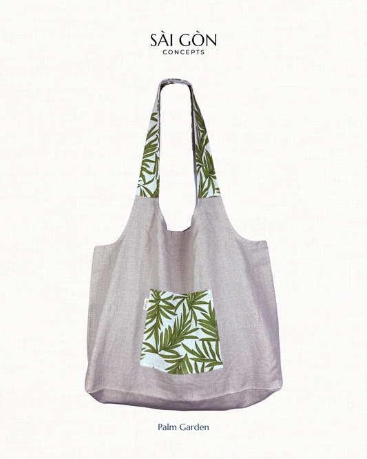 Saigon Concepts own beach tote bag in natural linen with green palm leaf pattern on a white background.