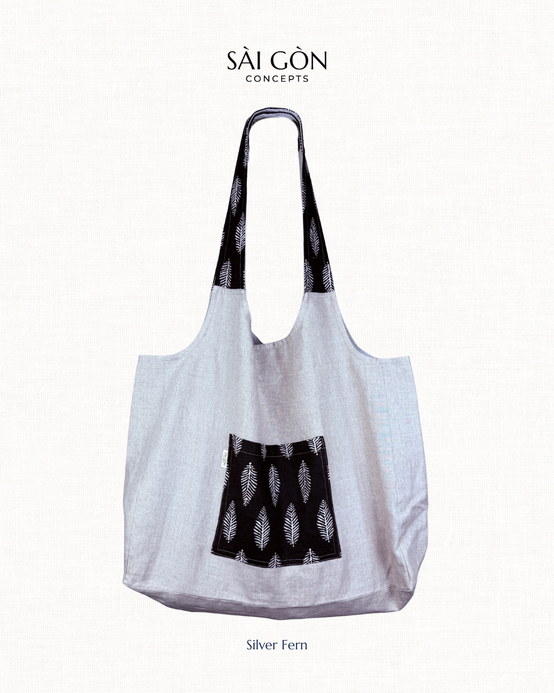 Saigon Concepts natural linen colour beach tote bag with black silver fern patterned pocket and handle on a white background