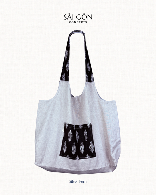 Saigon Concepts natural linen colour beach tote bag with black silver fern patterned pocket and handle on a white background