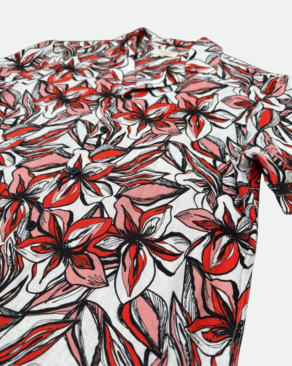 Red and black floral patterned Hawaiian shirt on a white background - lay flat side view