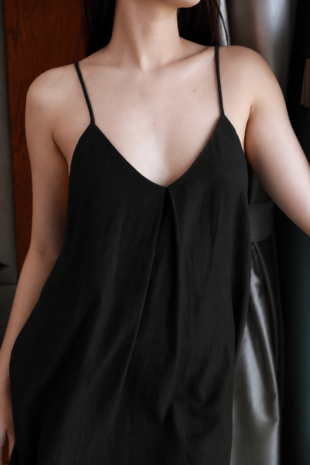 Person wearing a black slip dress with thin straps.
