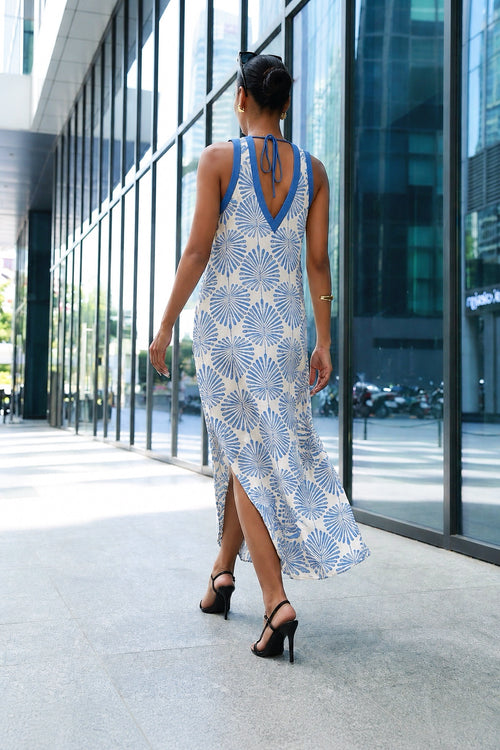 Woman wearing a light blue patterned halter dress, back view walking outdoors