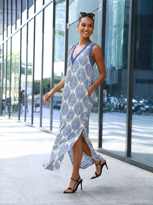 Woman wearing a light blue patterned halter maxi dress, walking outdoors