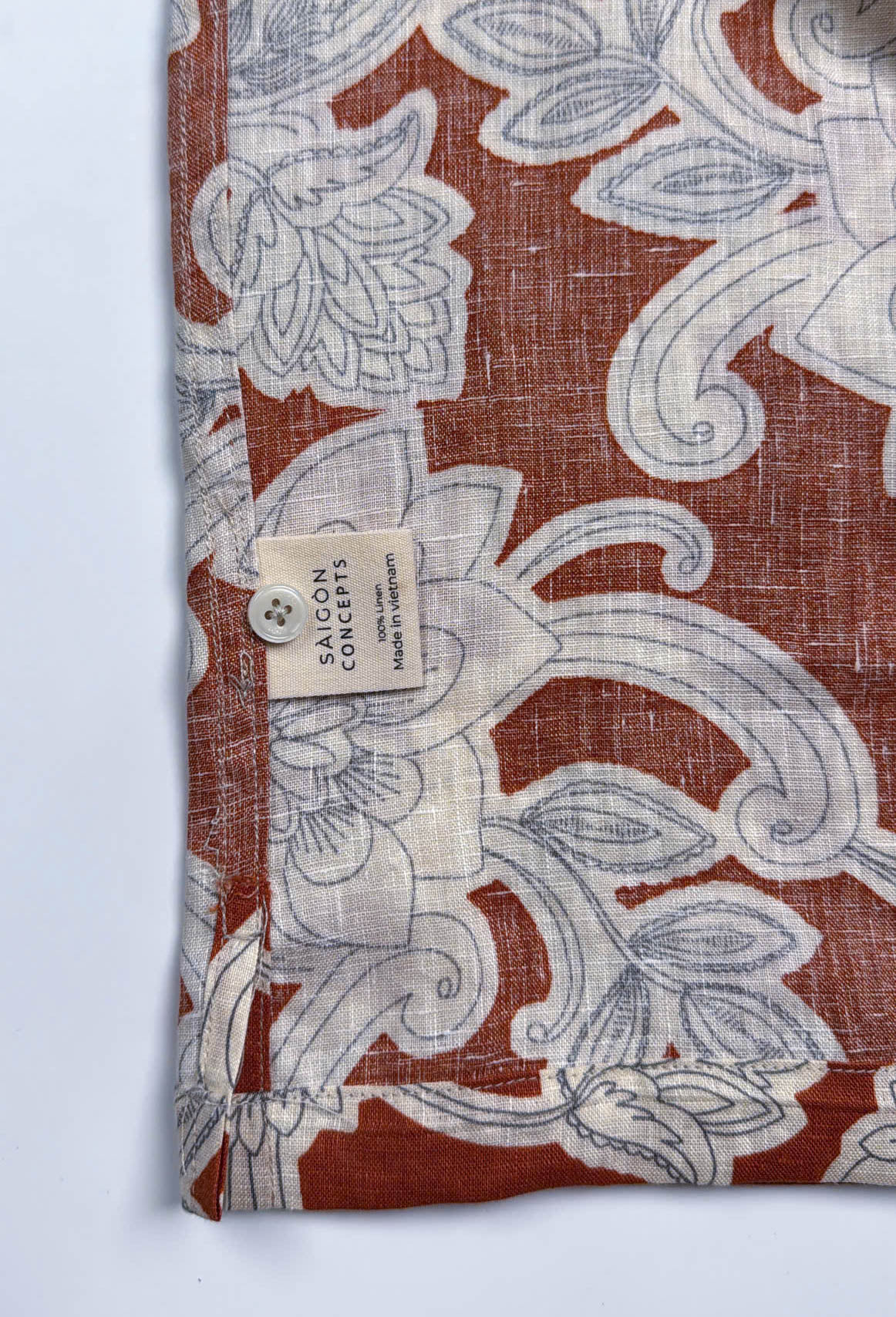 Saigon Concepts Annam Vine Hawaiian Shirt with white etched floral print on rust-orange linen fabric - care label detail view