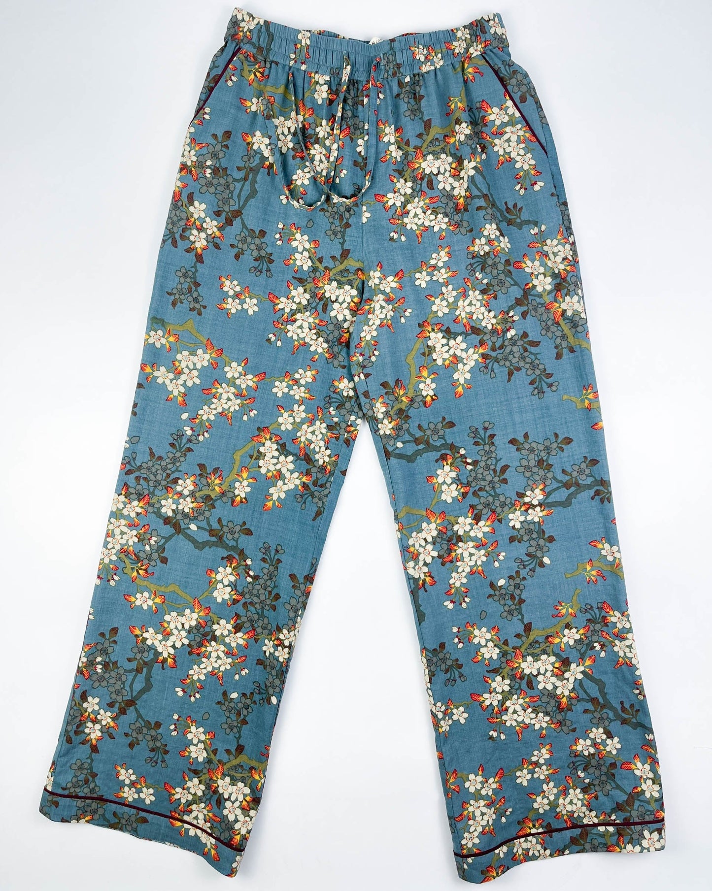 Flat front view of Long Pyjama pants in Teal Blue cotton-linen fabric with delicate white blossom print with contrast piping - Saigon Concepts