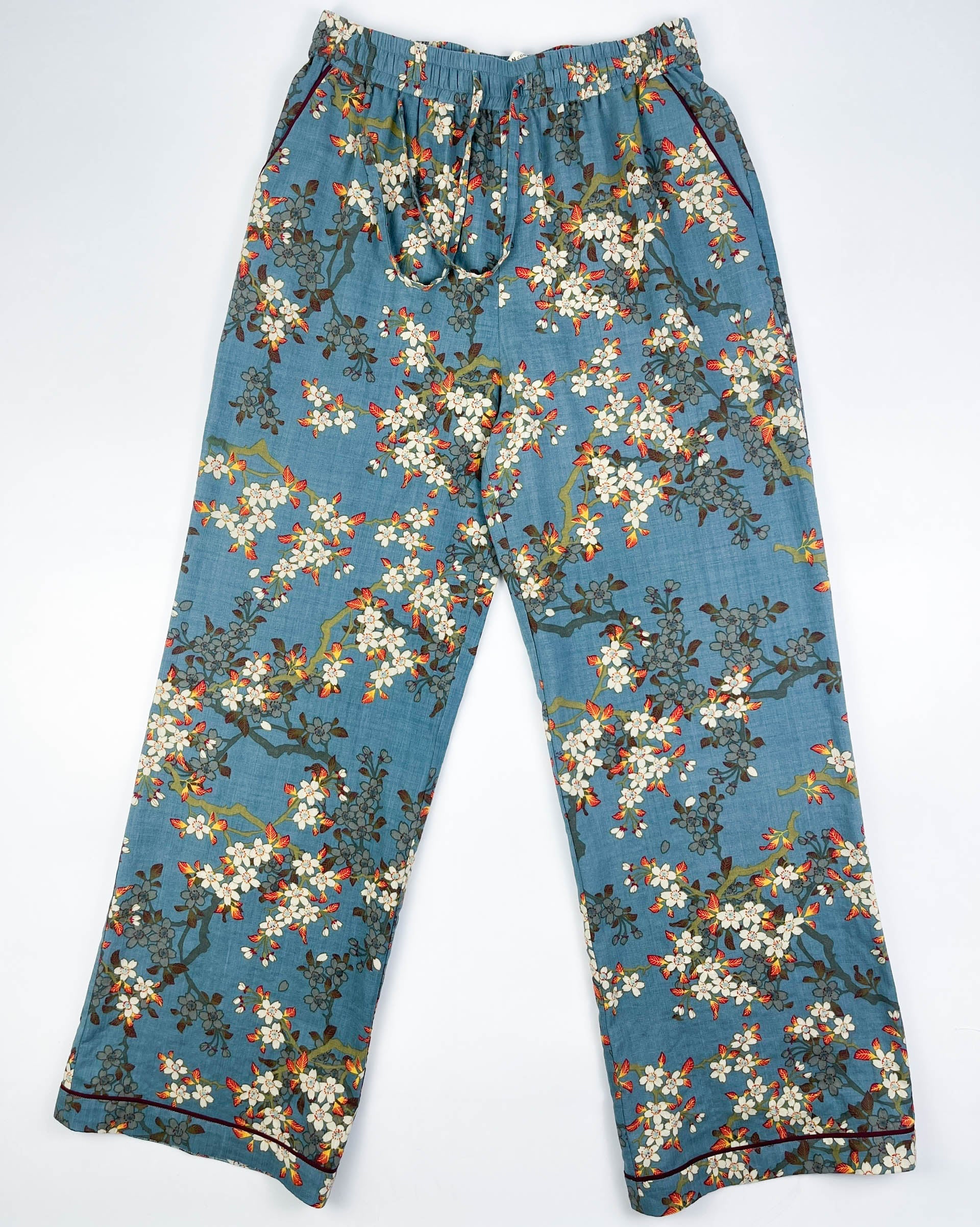 Flat front view of Long Pyjama pants in Teal Blue cotton-linen fabric with delicate white blossom print with contrast piping - Saigon Concepts