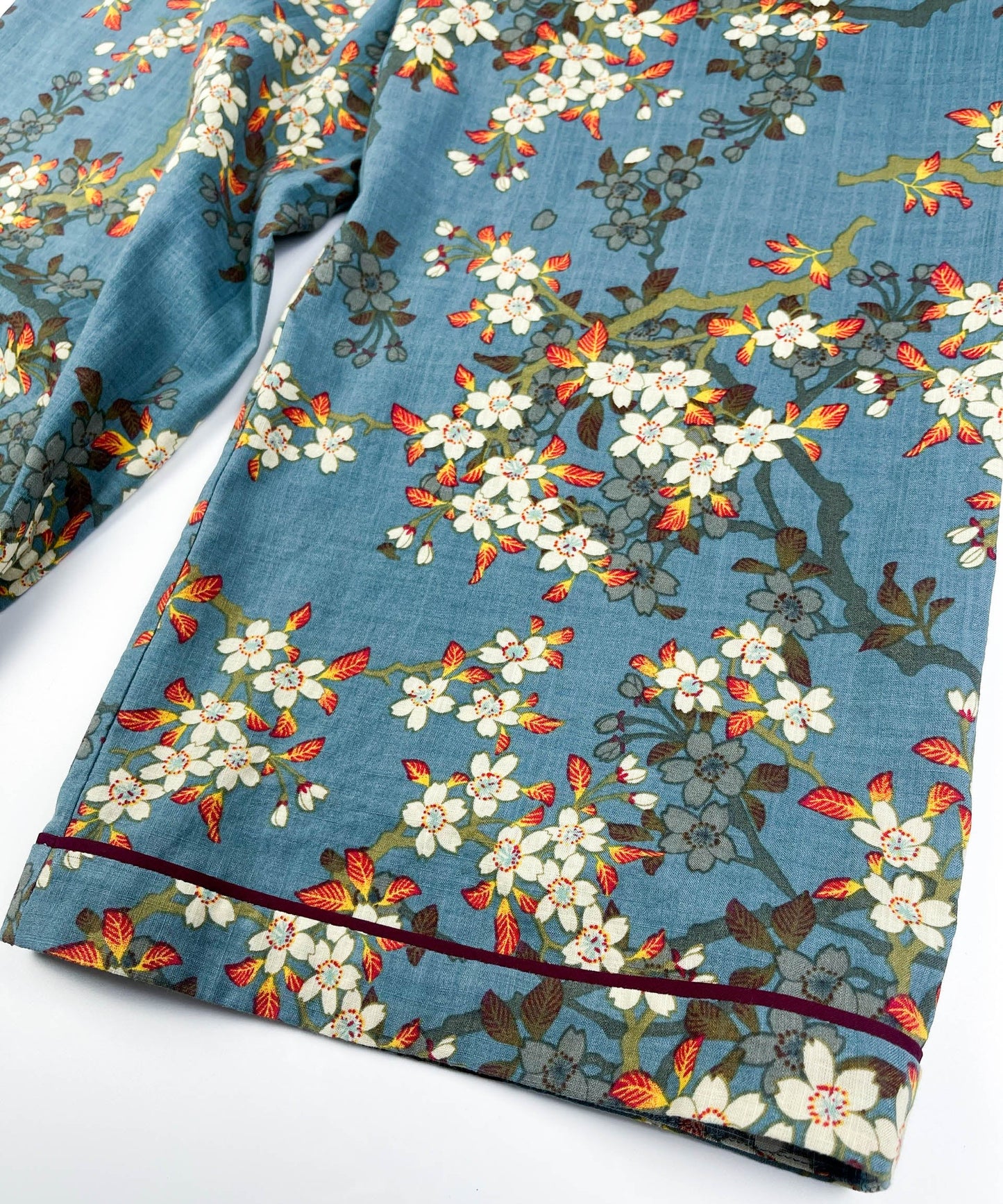 Leg seam detail of Long Pyjama pants in Teal Blue cotton-linen fabric with delicate white blossom print with contrast piping - Saigon Concepts