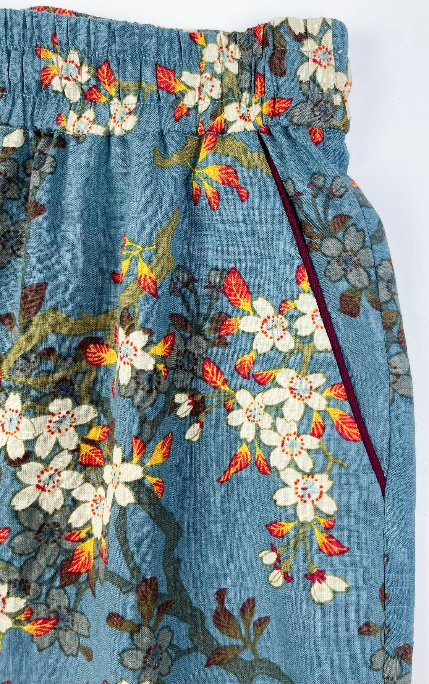 Front pocket detail view of Long Pyjama pants in Teal Blue cotton-linen fabric with delicate white blossom print with contrast piping - Saigon Concepts