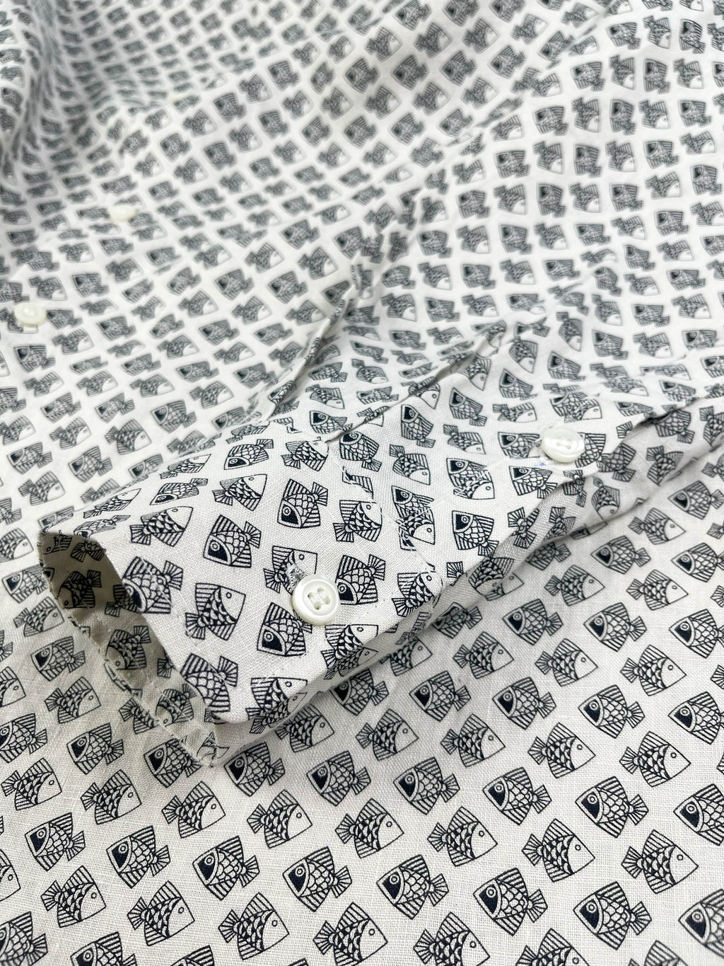 Tiny Black Fish linen long sleeve button-up shirt lay flat cuff detail view, small fish print on natural white base