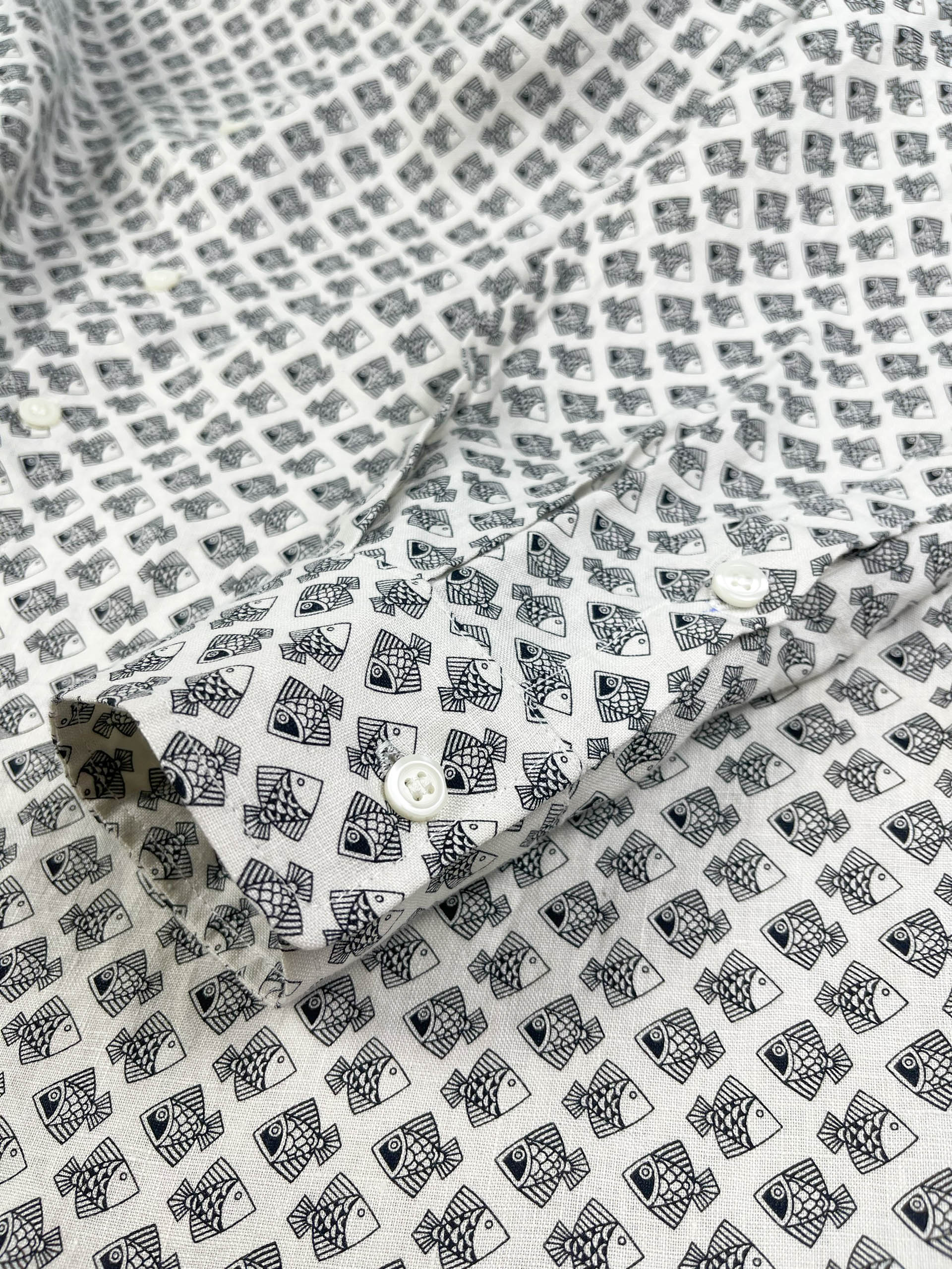 Tiny Black Fish linen long sleeve button-up shirt lay flat cuff detail view, small fish print on natural white base