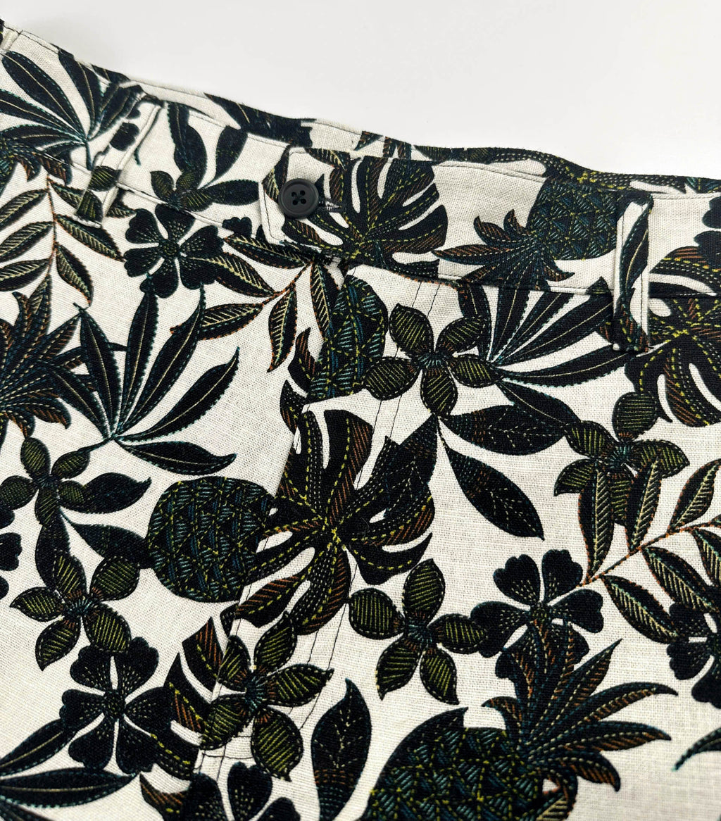 Close up of front zipper of black tropical floral patterned linen shorts on a natural white background