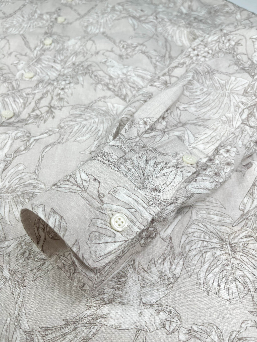 Tropicana Parrot long sleeve button-up shirt lay flat cuff detail view, parrot and foliage print on natural white linen
